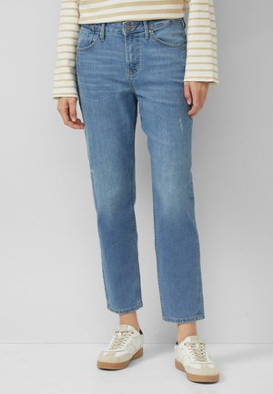 Light blue denim jeans with a straight cut and minor fading details, paired with white sneakers featuring a beige sole.