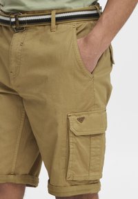 Shorts cargo kaki en tissu léger. Présentent des ourlets roulés, des poches latérales et un patch de marque. Accentué par une ceinture rayée.