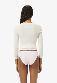 Witte geribbelde cropped sweater met lange mouwen, gecombineerd met lichtroze hipsterondergoed met een logo tailleband. Eenvoudig achteraanzicht.