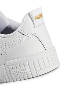 Zapatilla blanca de cuero con acabado texturizado, cuello acolchado y suela de goma elevada. Presenta un pequeño logo dorado de "PUMA" en el talón.