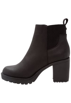 Black ankle boot made of smooth material with a textured elastic side panel, thick block heel, and a rugged sole for traction.