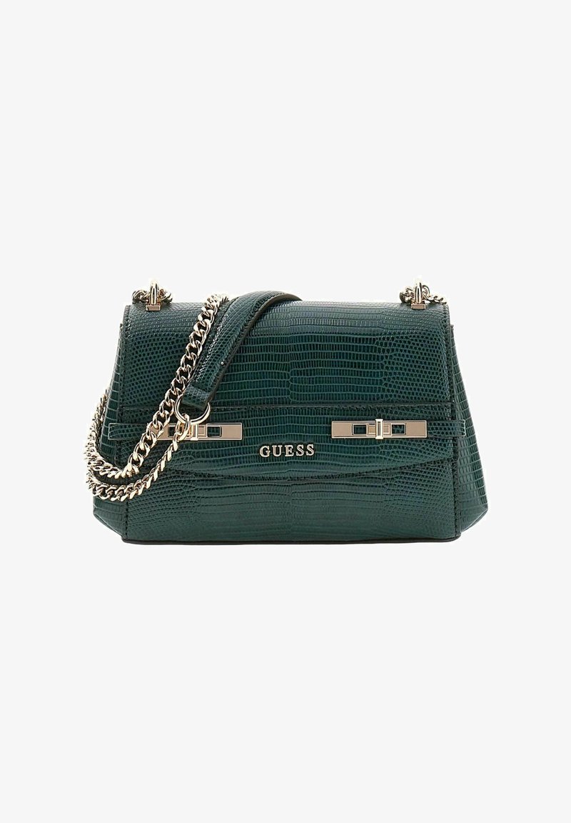 Sac à main en cuir synthétique vert imitation crocodile avec une forme structurée. Il est doté d'une bandoulière chaîne et de ferrures dorées, avec l'inscription "GUESS" à l'avant.