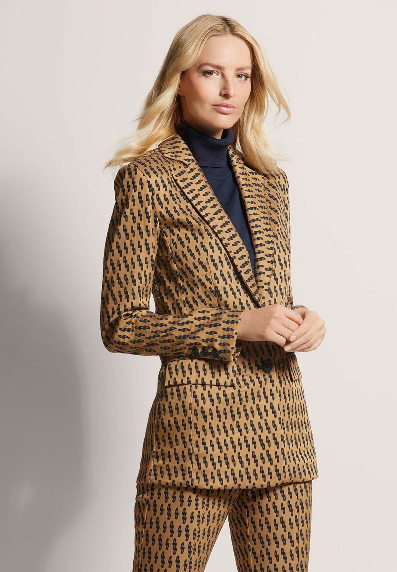 Bruine geblokte blazer en bijpassende broek met een zwart abstract ontwerp, gemaakt van een soepele stof met een gestructureerde pasvorm.