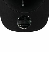 Czarna czapka z płaskim daszkiem, okrągła naszywka z logo z tekstem oraz teksturowanym materiałem. Regulowane zapięcie snapback zapewniające odpowiednie dopasowanie.