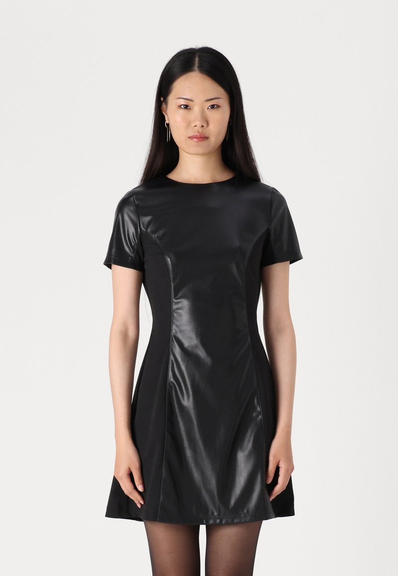 Robe noire à manches courtes, en simili cuir lisse, corsage ajusté, jupe évasée et coutures minimales. Accentuée d'un éclat subtil.