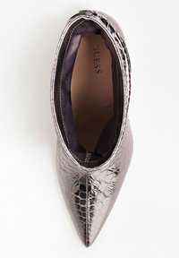 Stivale alla caviglia argentato metallico con punta appuntita e texture coccodrillo, etichettato "GUESS" sulla soletta imbottita color tan, mostrato dall'alto.