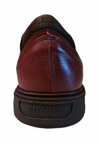 Zapato de cuero marrón con puntera redondeada, cuello de tejido negro texturizado y suela de goma negra que muestra el nombre de la marca. Detalle de costura sutil visible.
