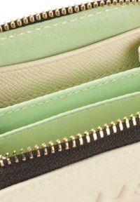 Cartera con tres compartimentos; materiales en crema texturizada, verde claro y verde pálido liso, con acentos de cremallera dorada.