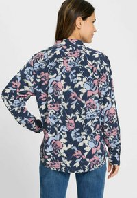 Langärmliges Hemd in Marineblau mit floralem Muster in Rosatönen, Blau und Creme. Weicher Stoff mit lockerer Passform und spitzem Kragen.