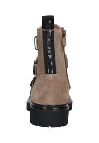 Bruine suède enkellaarsjes met een zwarte stoffen lus en gespaccenten. Dikke zwarte rubberen zool met een gestructureerd grippatroon.