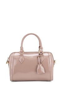 Borsa in vernice di colore rosa chiaro, con hardware dorato, due manici e un piccolo charm. Forma arrotondata con dettagli delle cuciture.