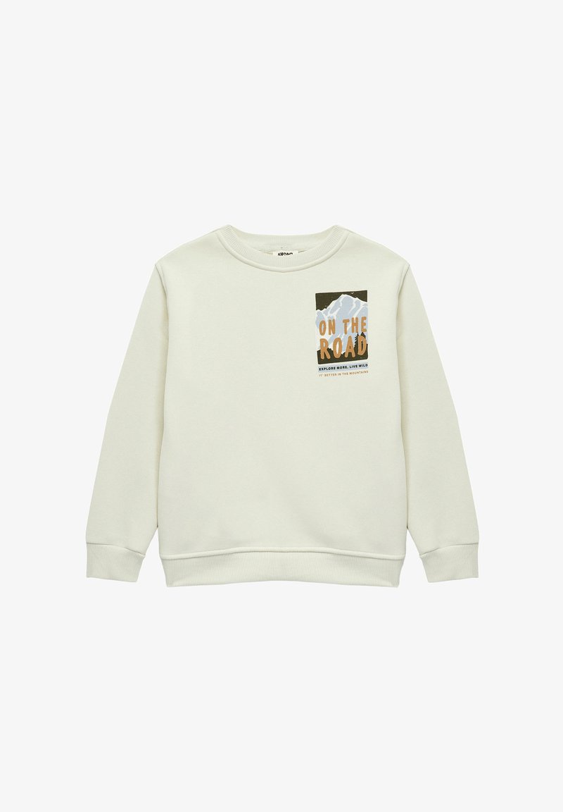 Sweat-shirt beige clair en tissu doux, avec un graphique de montagne et le texte "EN ROUTE" en orange et noir. Poignets et ourlet côtelés.