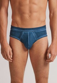 Herrenunterhosen aus dunkelblauem Stoff mit weicher Textur, breitem Bund und konturiertem Vorderteil. Keine sichtbaren Logos oder Muster.