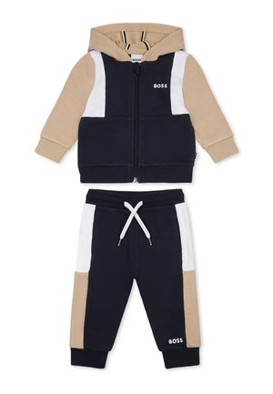Ensemble de survêtement zippé à capuche en bleu marine, beige et blanc. Tissu doux, avec un design coloré en blocs et un pantalon à cordon de serrage ajustable.