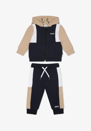 Tuta con zip e cappuccio in blu navy, beige e bianco. Tessuto morbido, con design a blocchi di colore e pantaloni regolabili con coulisse.