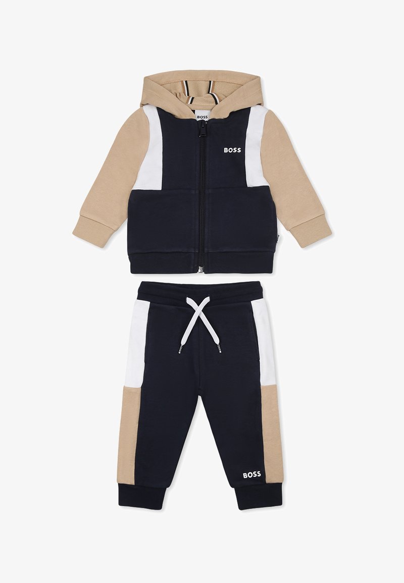 Dres z kapturem rozpinany, w kolorze granatowym, beżowym i białym. Miękka tkanina, z wielokolorowym wzorem oraz regulowanymi spodniami z sznurkiem.