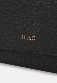 Schwarze Textur-Geldbörse mit einer glatten Oberfläche und geprägten Nähten. Verfügt über ein goldenes "LIU•JO"-Logo auf der Vorderseite zur Markenkennzeichnung.