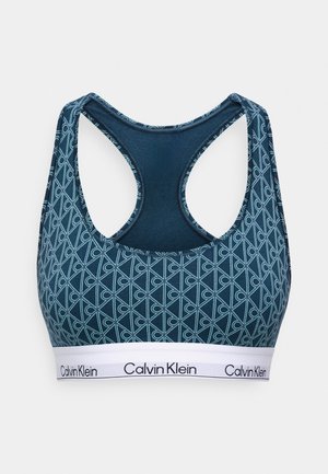 Calvin Klein Sport-BH in dunkeltürkis mit geometrischem Muster in hellblau und einem weißen elastischen Band, das den Markennamen zeigt.