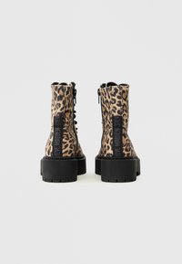 Sorte ankelstøvler med leopardprint, tekstureret stof, sort kraftig sål og lynlåse i siderne. Har et bageste label til branding.