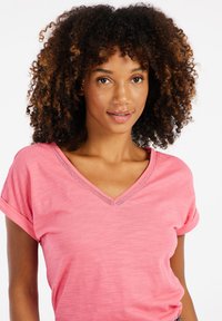Roze T-shirt met V-hals, korte mouwen, lichtgewicht stof, structuuraccenten langs de halslijn, casual pasvorm, glad oppervlak, zichtbare stikdetails.