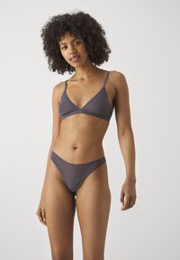 Ensemble de bikini gris sans couture comprenant un bralette triangulaire avec de fines bretelles et un bas thong assorti. Tissu doux avec une texture lisse.