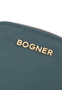 Teal najlon denarnica z zlatim logotipom "BOGNER", z gladko površino in vidnim zadrgo po zgornjem robu.