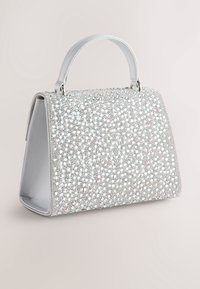 Bolso de mano plateado cubierto de brillantes strass, con un diseño estructurado, asa corta y una textura suave en el forro interior.