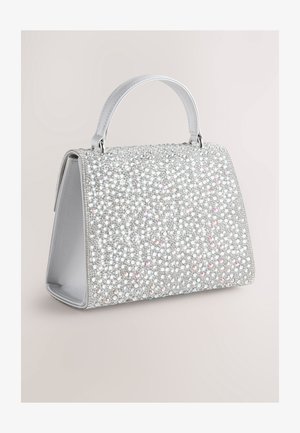 Srebrna torbica, prekrita s sijočimi kristali, z urejeno zasnovo, kratkim ročajem in gladko teksturo notranje podloge.