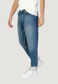 Jeans dritti azzurri con un lavaggio leggermente sbiadito, cinque tasche e una vestibilità alla moda e rilassata, abbinati a sneakers bianche.