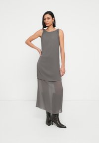 Γκρι αμάνικο φόρεμα με στρωματοποιημένο σχέδιο, κατασκευασμένο από απαλό ύφασμα. Διαθέτει ημιδιάφανο κάτω στρώμα και ίσια σιλουέτα.