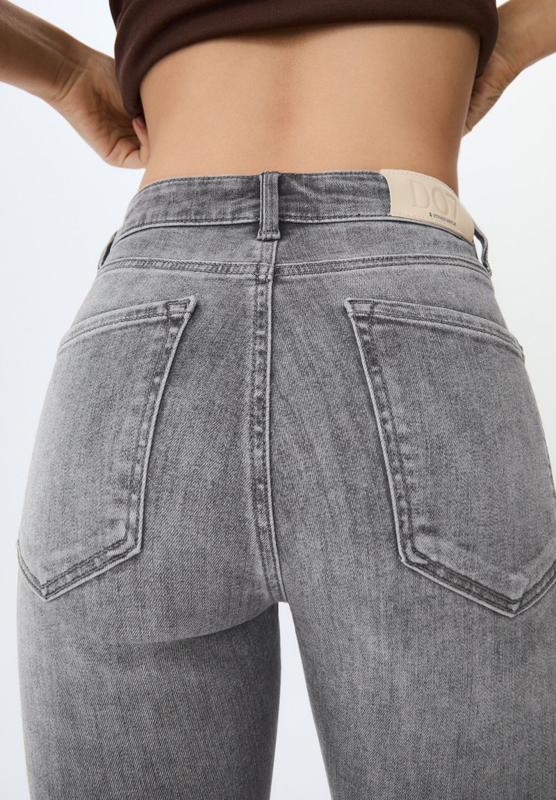 Jeans in denim grigio con vita alta, dotati di due tasche posteriori e un'etichetta in pelle con marchio all'altezza della vita. Texture liscia e design aderente.