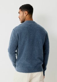 Maglione da uomo blu in lana con scollo rotondo, finitura testurizzata e polsini e orlo a coste, caratterizzato da una vestibilità rilassata e un peso medio.