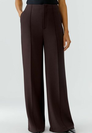 Hellefreie Hose aus dunkelbraunem Stoff, mit glatter Textur, seitlichen Taschen und hoher Taille mit dezenten Vorderfalten.