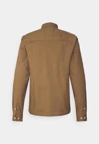 Veste-chemise marron à manches longues avec poignets à boutons, col montant et détail de couture sur le haut du dos.