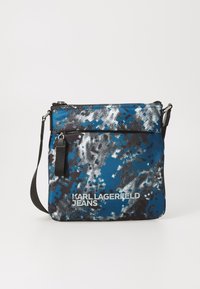 Modra in črna vzorčasta torba preko telesa z zadrgo, ki ima teksturirano površino in nastavljiv trak. Natisnjen logotip "Karl Lagerfeld Jeans".