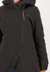 Ciemnoszara kurtka z kapturem wykonana z teksturowanej tkaniny, z ukośnym zamkiem błyskawicznym, bocznymi kieszeniami i małym logo w kształcie serca na piersi.