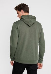 Olijfgroene hoodie, gemaakt van een katoenmix, met een klassiek ontwerp, lange mouwen en een kangoeroezak. Matte, zachte textuur.