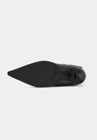 Black pointed-toe shoe with a sleek design, suede material, rubber sole, and minimal hardware details on the upper. Flat construction on the bottom.