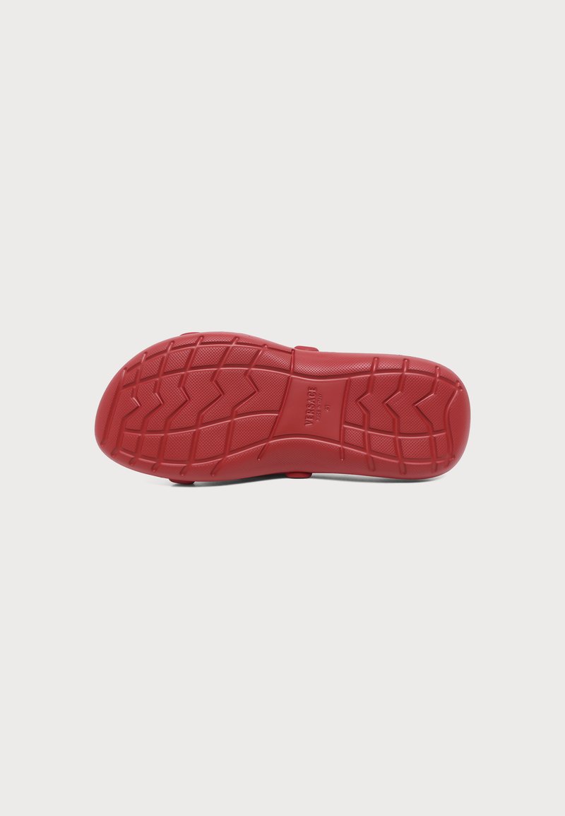 Rote Gummisohle eines Schuhs mit strukturiertem Zickzack-Profil und mittig eingeprägtem "Versace"-Logo.