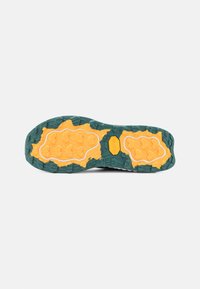 Shoe sole designed with green and yellow rubber, featuring textured patterns for traction. Includes visible branding element in the center.