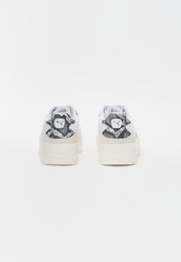Baskets à plateforme avec tige en similicuir blanc, accents texturés en peau de serpent noir et blanc, et logo Puma distinctif au talon.