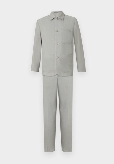 Ανοιχτό γκρι κοστούμι κατασκευασμένο από λείο ύφασμα, με σακάκι που κουμπώνει και μία τσέπη, και αντίστοιχες παντελόνες με ίσια πόδια.
