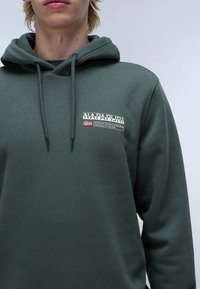 Groene hoodie van katoen, met een voorvak, koordjes en een logopatch op de linkerborst met tekst en de Noorse vlag.