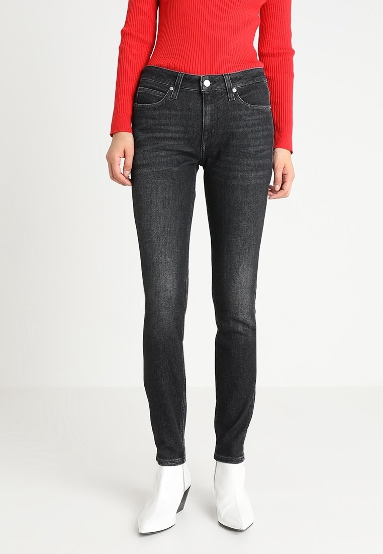 Svarta smala jeans med en slät yta, midja med medelhöjd, framfickor och silverdetaljer. Bärs med en röd ribbad topp och vita ankelstövlar.