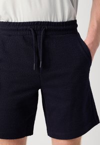 Marineblå teksturerte shorts med elastisk liv og snøring, med sidelommer og avslappet passform.