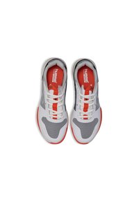 Zapatillas deportivas en blanco y gris, elaboradas con materiales de malla y sintético. Presentan acentos y cordones rojos, con una forma distintiva para mayor comodidad.