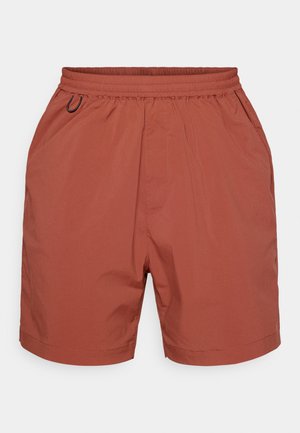 Rust-colored shorts made from lightweight, smooth fabric. Features an elastic waistband and a loose fit. No pockets or visible fastenings.