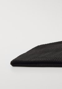 Czarna żeberkowana tkanina złożona pod kątem, ukazująca teksturowaną powierzchnię i wąskie, pionowe linie. Miękki, lekki materiał o prostych krawędziach.