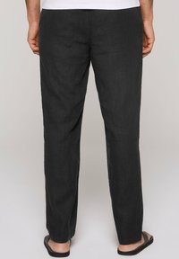 Donkergrijze linnen broek met een relaxte pasvorm. Heeft een rechte pijp en een elastische tailleband, gecombineerd met teenslippers.