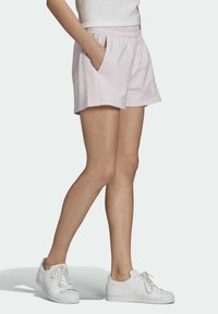 Lichtroze katoenen shorts met een elastische tailleband, zijzakken en verticale gestreepte details, gecombineerd met witte sneakers.